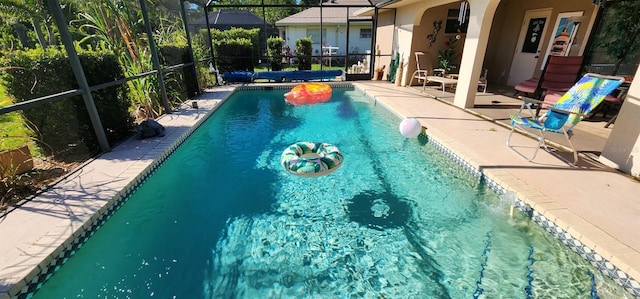 view of swimming pool featuring a patio and glass enclosure