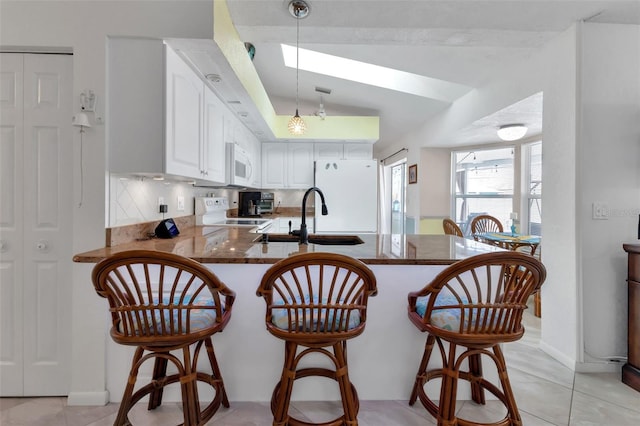 kitchen with white appliances, backsplash, white cabinetry, decorative light fixtures, and kitchen peninsula