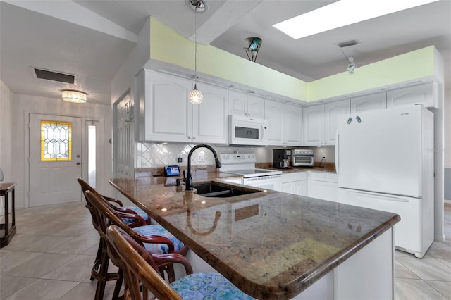 kitchen with white appliances, white cabinetry, a breakfast bar area, hanging light fixtures, and kitchen peninsula