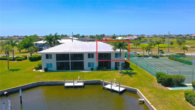 back of property with a lawn and a water view