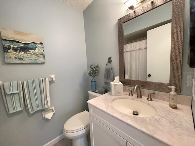 bathroom with a textured ceiling, vanity, and toilet