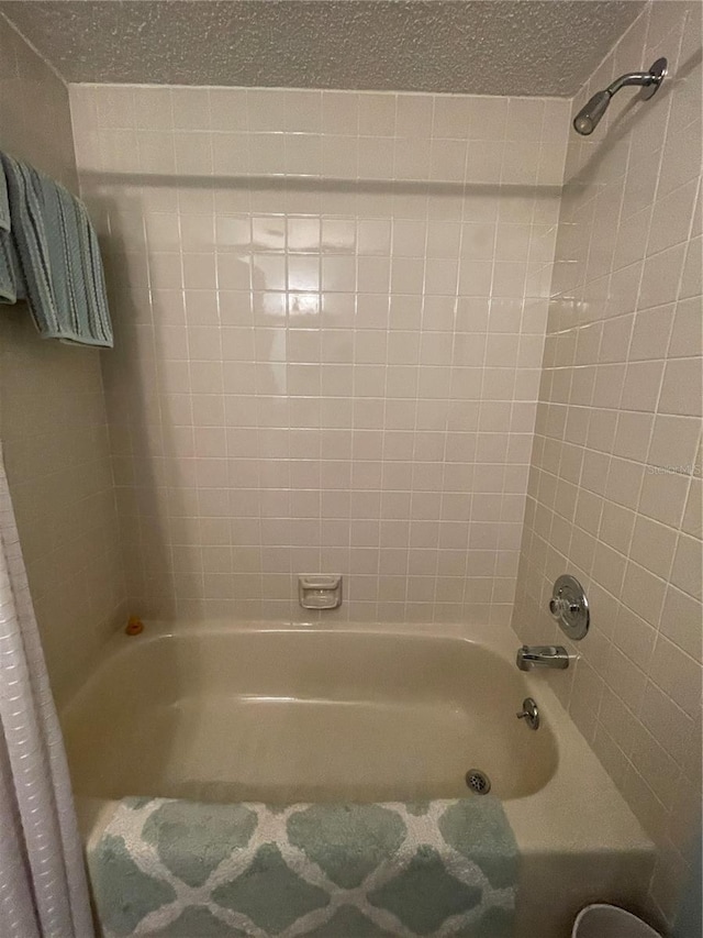 bathroom with shower / bath combo with shower curtain and a textured ceiling