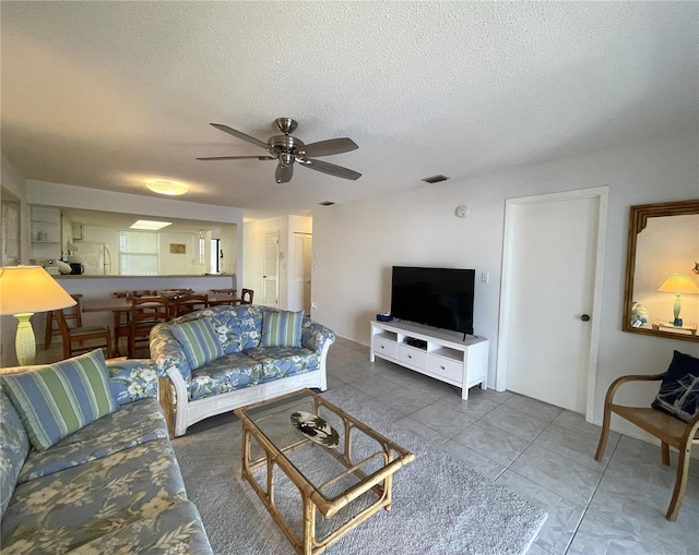 tiled living room featuring ceiling fan and a textured ceiling