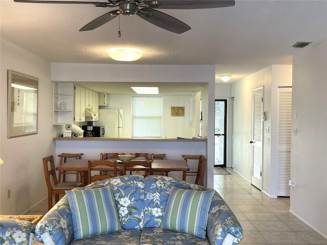 living room with light tile patterned floors, a textured ceiling, and ceiling fan