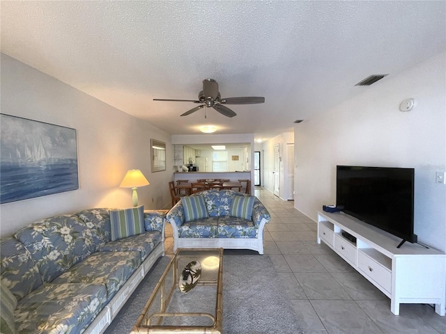 tiled living room with ceiling fan and a textured ceiling