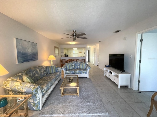 living room with tile patterned flooring, a textured ceiling, and ceiling fan