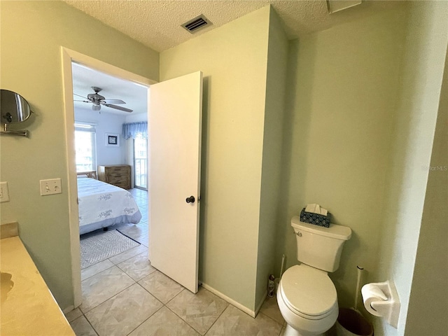 bathroom with ceiling fan, tile patterned flooring, a textured ceiling, toilet, and vanity