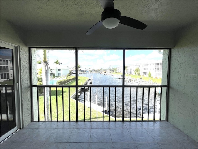 unfurnished sunroom with a water view and ceiling fan