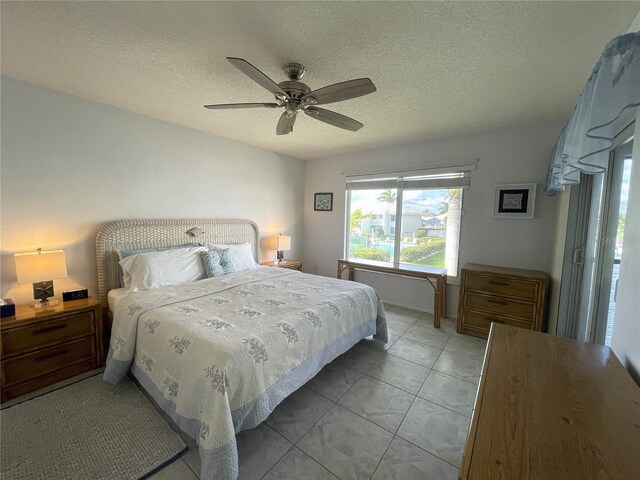 bedroom with ceiling fan, light tile patterned floors, and a textured ceiling