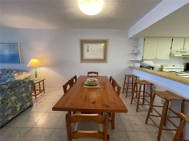 tiled dining room featuring a textured ceiling