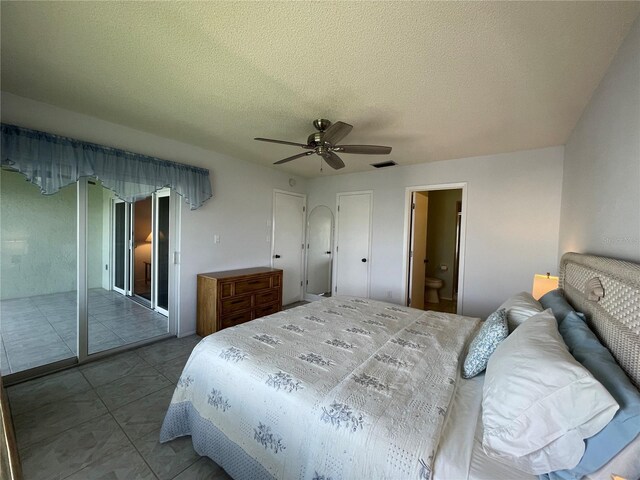 tiled bedroom with access to exterior, a textured ceiling, ensuite bathroom, and ceiling fan