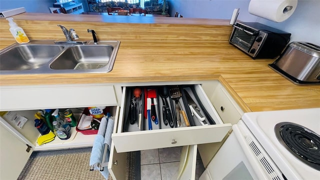 kitchen featuring white cabinets, tile patterned floors, and sink