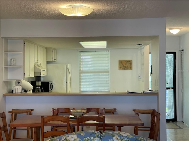 kitchen featuring white cabinets, white fridge, and a textured ceiling