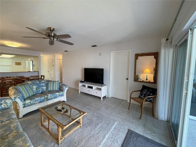 living room with a ceiling fan, visible vents, and a textured ceiling