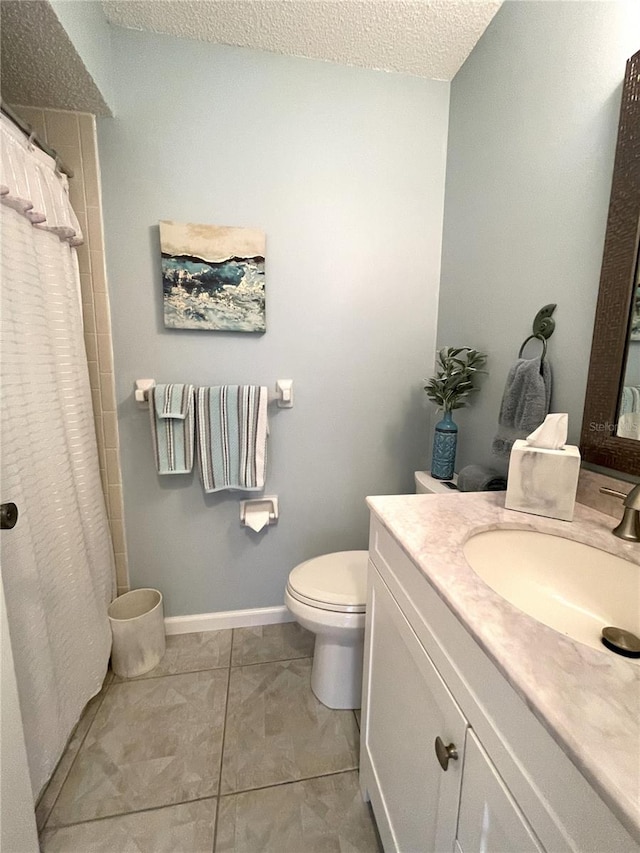 bathroom with tile patterned flooring, vanity, a textured ceiling, and toilet