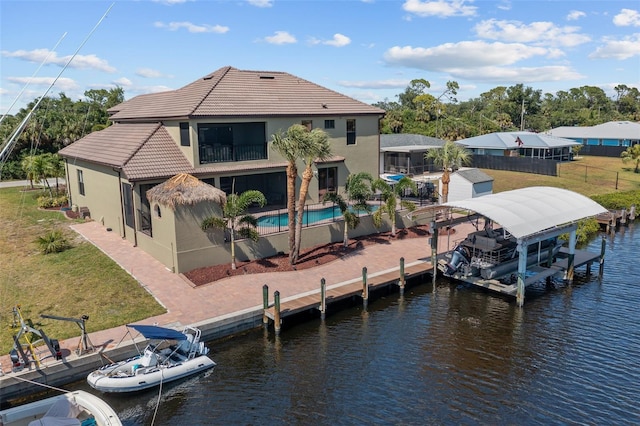 dock area with a fenced in pool, a water view, and a lawn