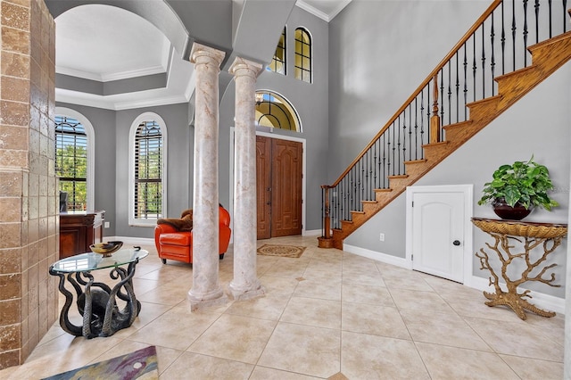 entrance foyer with ornate columns, crown molding, light tile flooring, and a raised ceiling