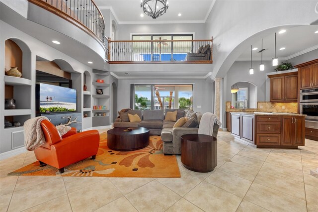 living room with light tile flooring, crown molding, a towering ceiling, and a chandelier