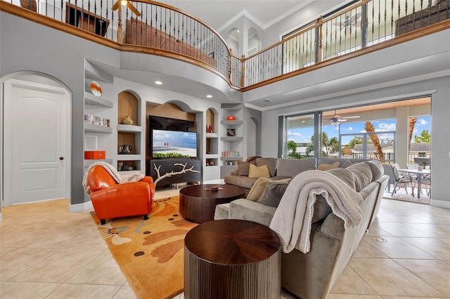 living room featuring a towering ceiling, light tile flooring, built in features, and ornamental molding