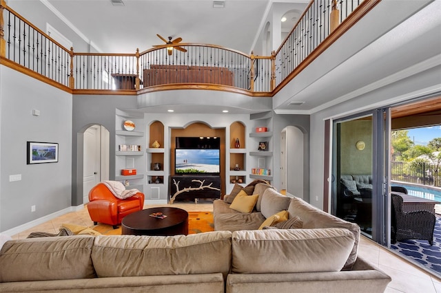 tiled living room featuring built in shelves, ceiling fan, and a high ceiling