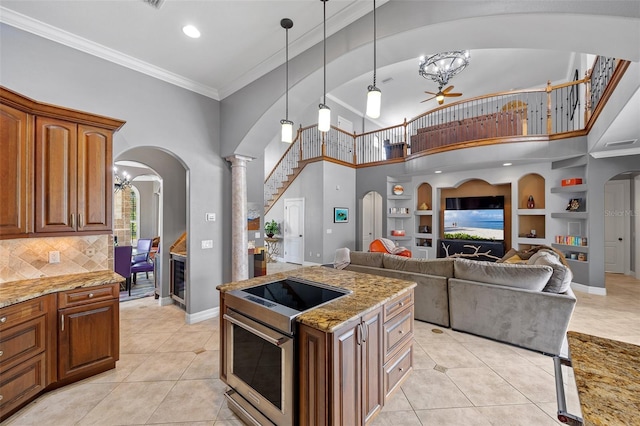 kitchen with backsplash, hanging light fixtures, light tile floors, and light stone countertops