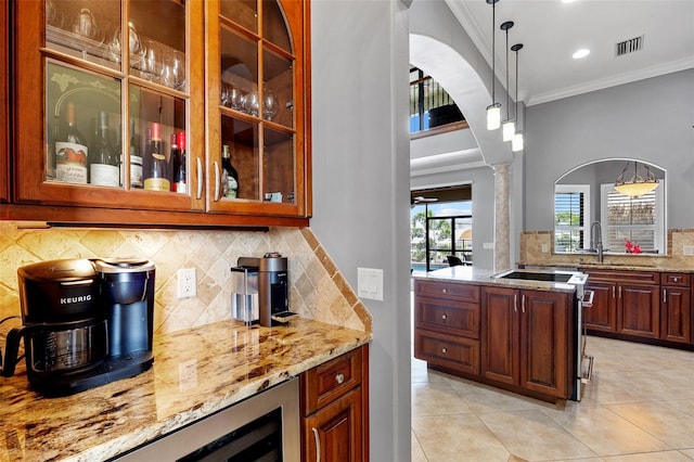 kitchen featuring hanging light fixtures, light stone countertops, ornamental molding, tasteful backsplash, and ornate columns