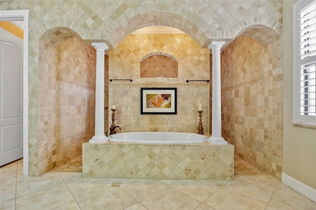 bathroom with a healthy amount of sunlight, tile flooring, ornate columns, and tiled bath