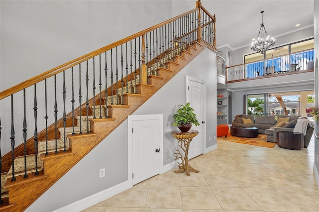 stairway with a chandelier, crown molding, tile floors, and a towering ceiling