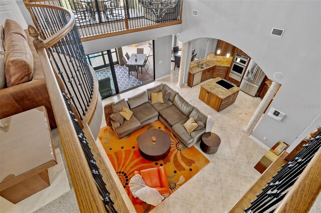 tiled living room with sink, a notable chandelier, and a high ceiling