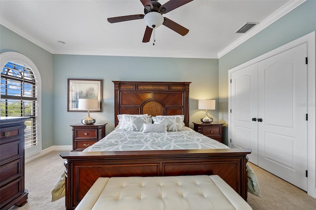 bedroom with ornamental molding, ceiling fan, light carpet, and a closet