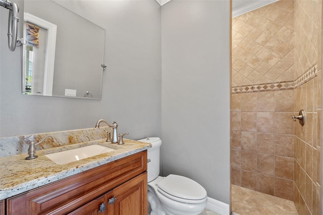 bathroom featuring ornamental molding, vanity, a tile shower, and toilet