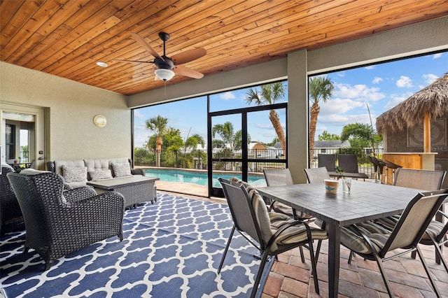 sunroom / solarium featuring a healthy amount of sunlight, wooden ceiling, and ceiling fan