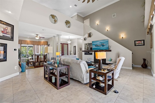 living room with ceiling fan, a towering ceiling, light tile flooring, ornamental molding, and ornate columns