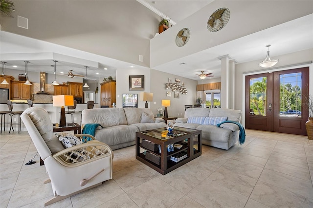 living room featuring ceiling fan, light tile flooring, and a towering ceiling