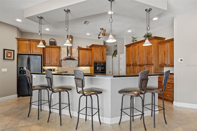 kitchen featuring a breakfast bar area, wall chimney range hood, pendant lighting, and black appliances