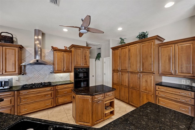 kitchen with ceiling fan, light tile flooring, black appliances, wall chimney range hood, and dark stone countertops