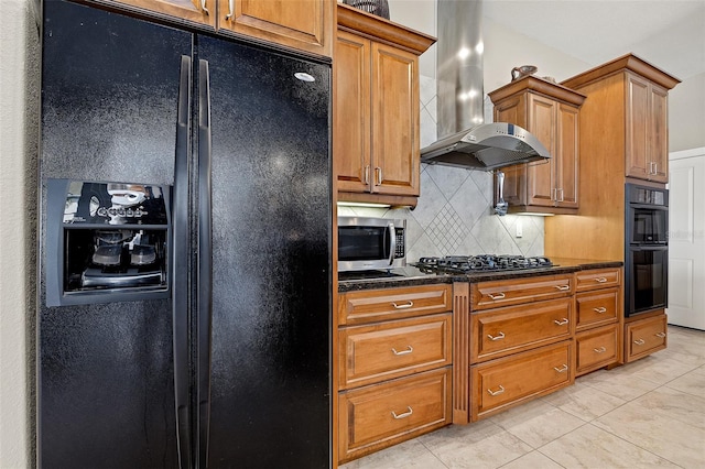 kitchen featuring wall chimney exhaust hood, light tile floors, tasteful backsplash, dark stone counters, and black appliances