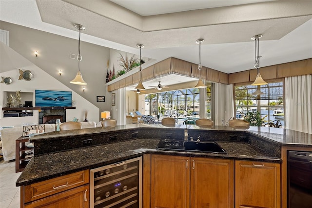 kitchen featuring dark stone countertops, decorative light fixtures, sink, and beverage cooler