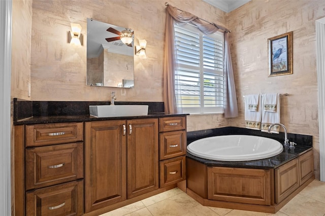 bathroom with ornamental molding, a bathing tub, ceiling fan, and vanity with extensive cabinet space