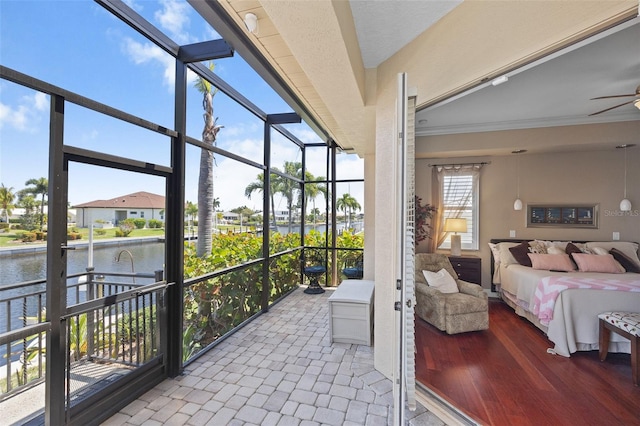 sunroom featuring ceiling fan and a water view