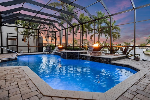 pool at dusk featuring an outdoor hot tub, a lanai, pool water feature, and a patio area