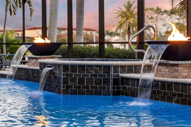 pool at dusk featuring pool water feature