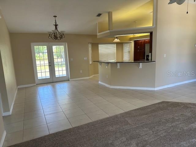 kitchen with hanging light fixtures, french doors, light carpet, and a chandelier