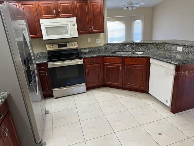 kitchen with appliances with stainless steel finishes, ceiling fan, light tile floors, sink, and dark stone counters