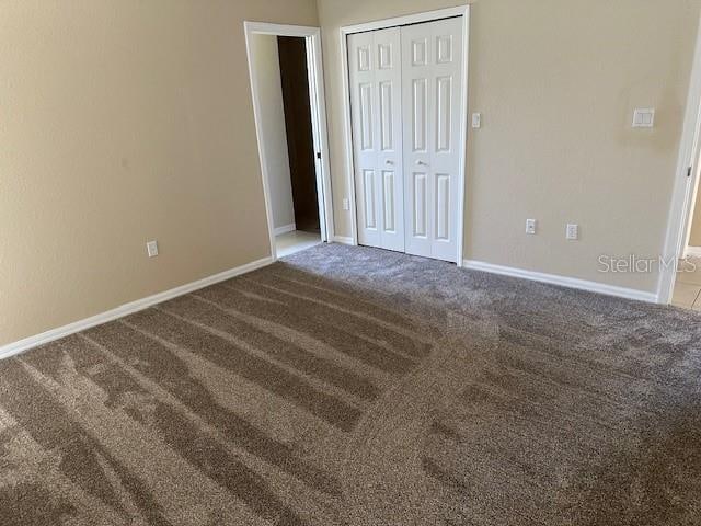 unfurnished bedroom with light colored carpet and a closet