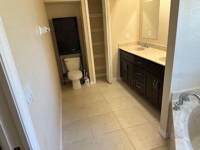 bathroom with a tub, toilet, tile floors, and vanity with extensive cabinet space