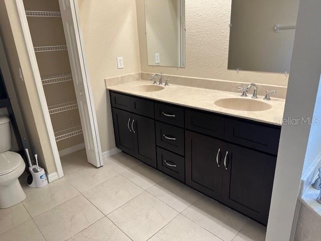 bathroom with tile floors, toilet, and dual vanity