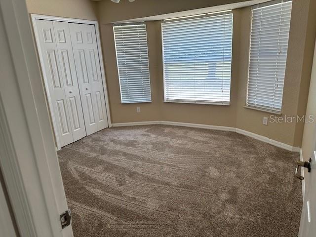 unfurnished bedroom featuring a closet and dark carpet