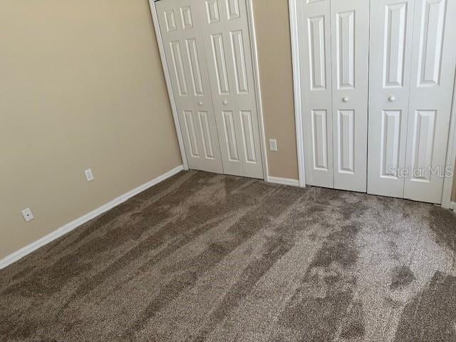 unfurnished bedroom featuring multiple closets and carpet flooring