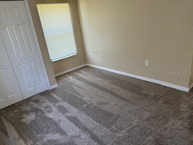 unfurnished bedroom featuring a closet and dark colored carpet